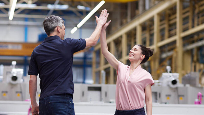 Coperion employees giving high five at assembly hall